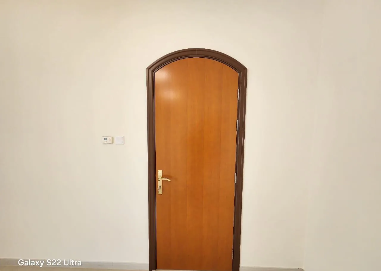 Arched wooden door with a honey finish and dark brown arched frame