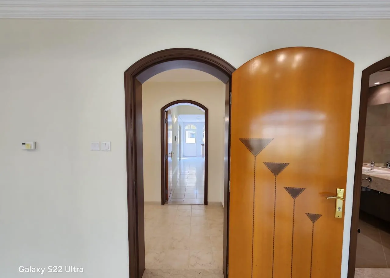 Open arched wooden door with an inlay design beside a dark brown arched frame