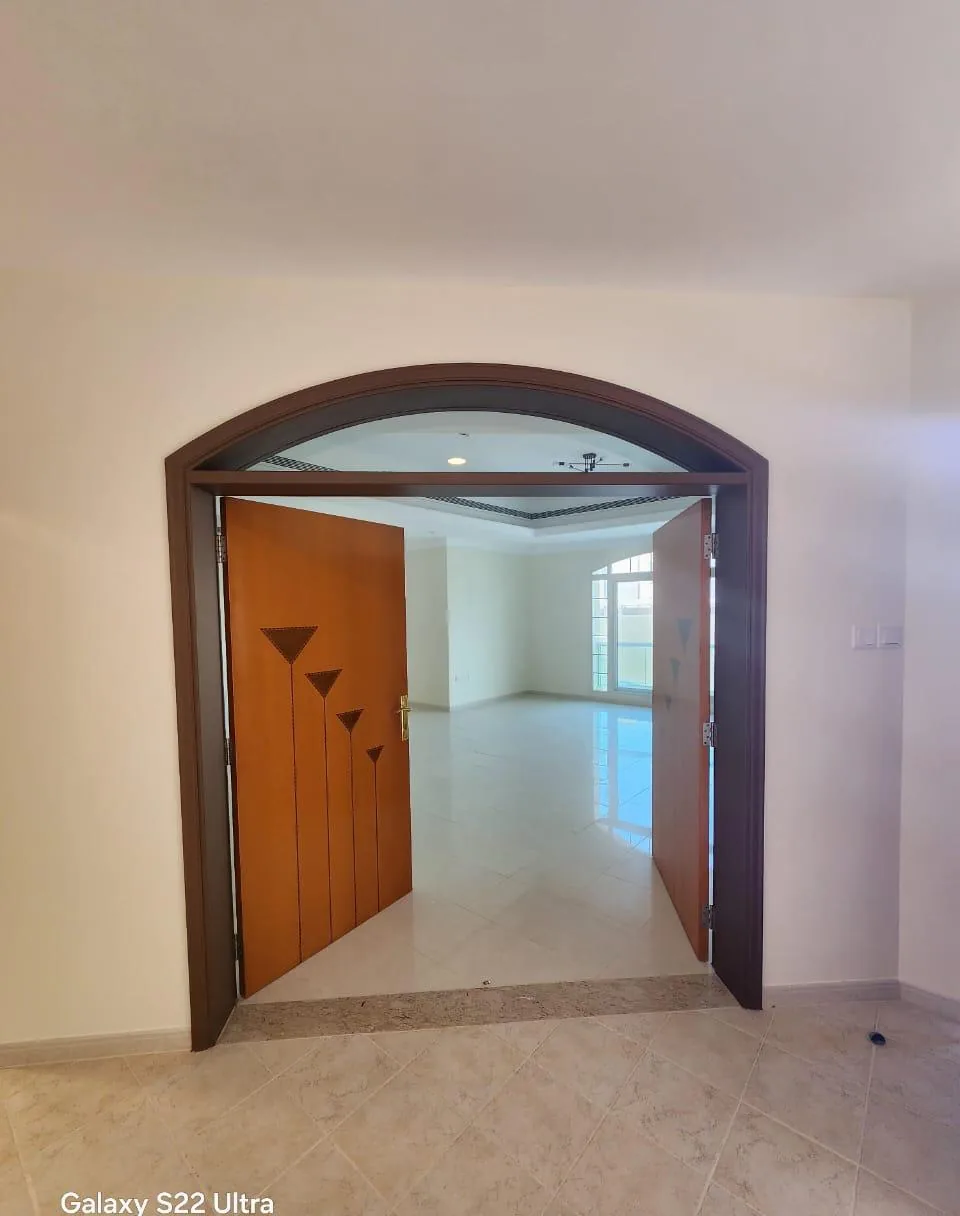 Double wooden door with an inlay design inside a dark arched frame