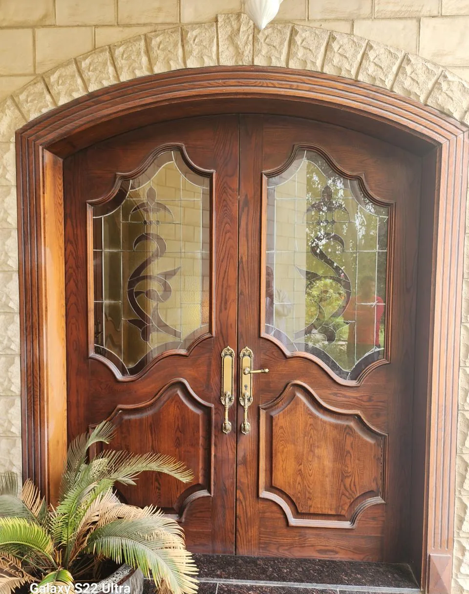 Double arched entrance door in dark stained wood with decorative glass