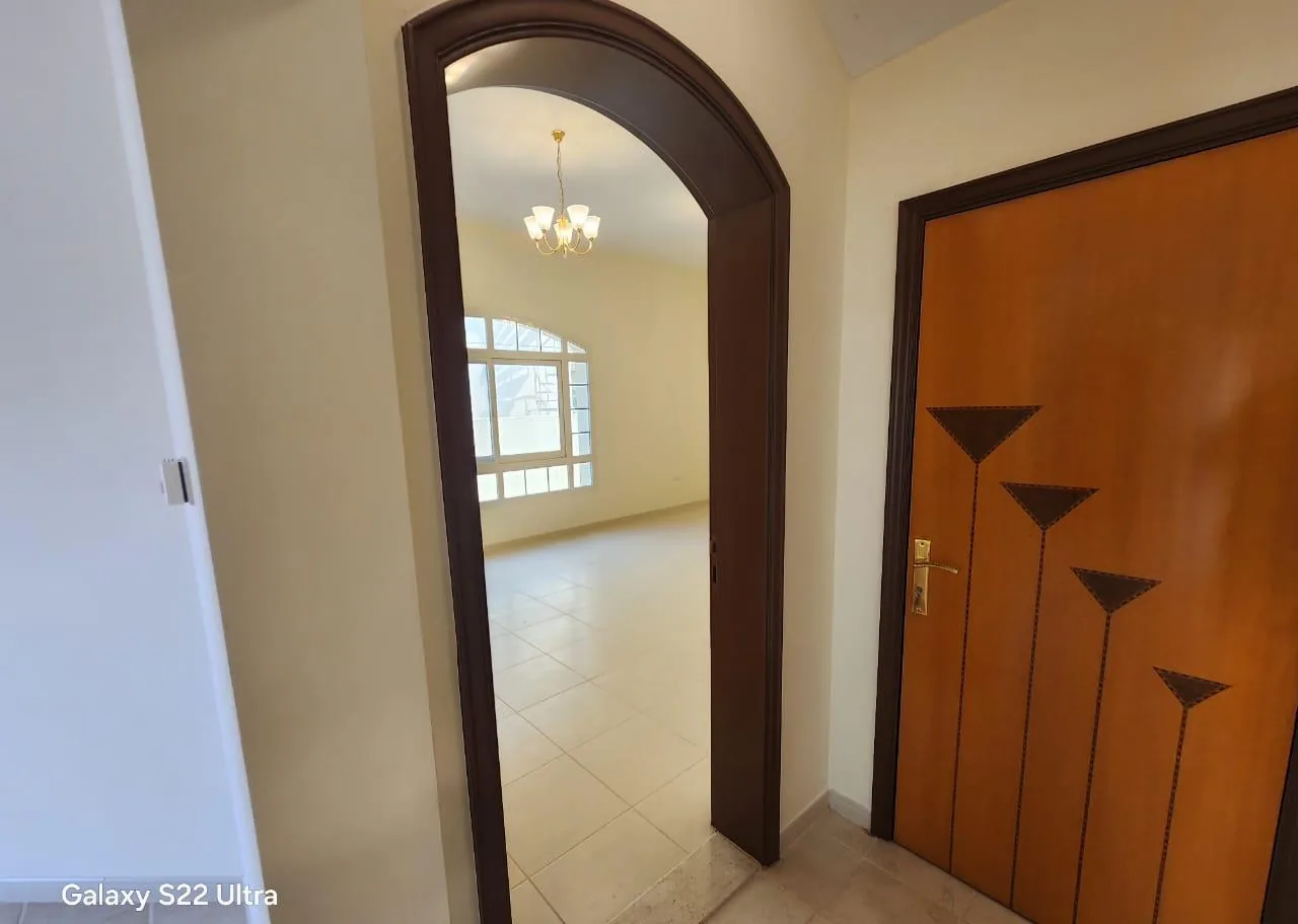 Wooden door with an inlay design next to a dark arched door frame