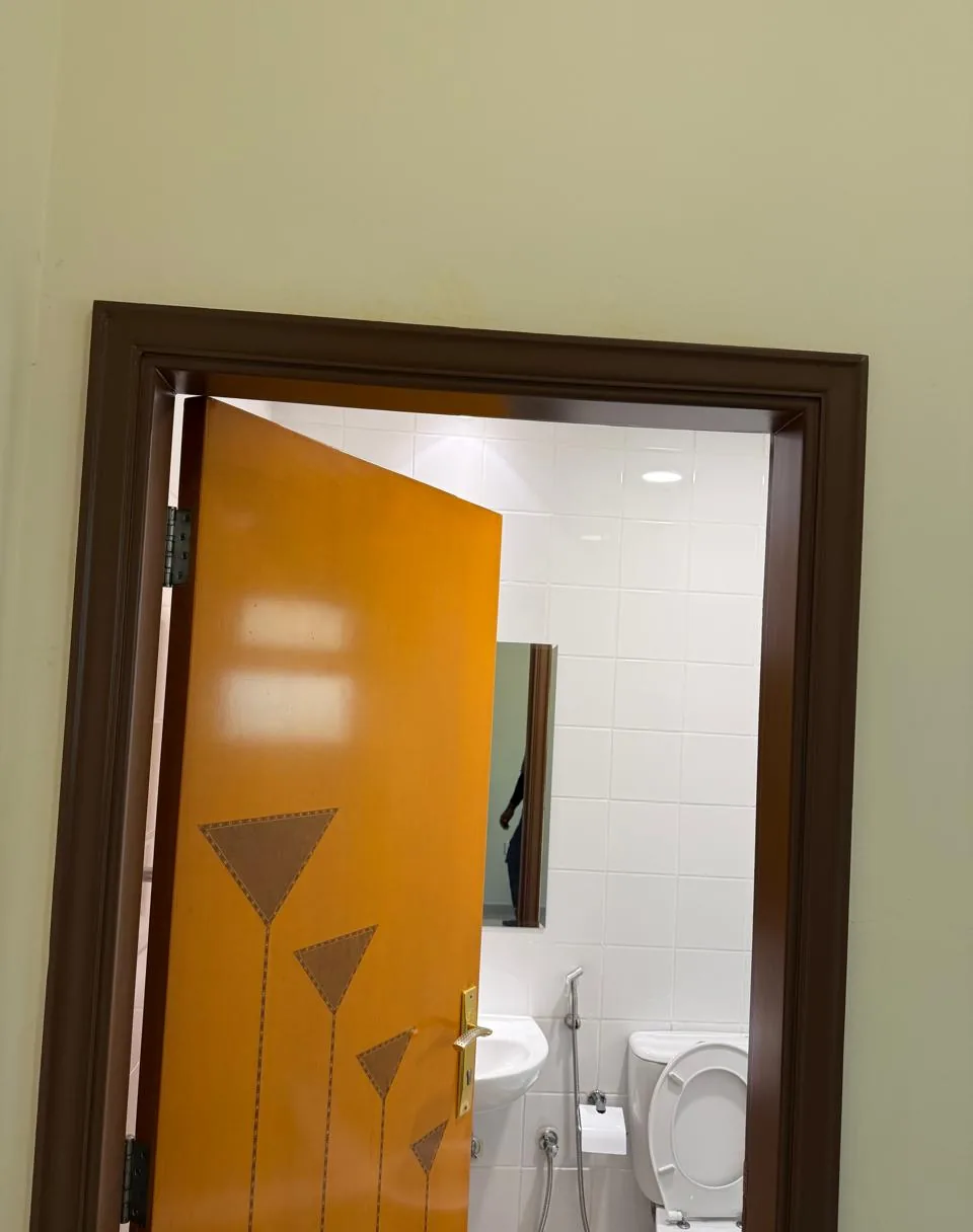 Orange wooden door with an inlay design opening onto a bathroom