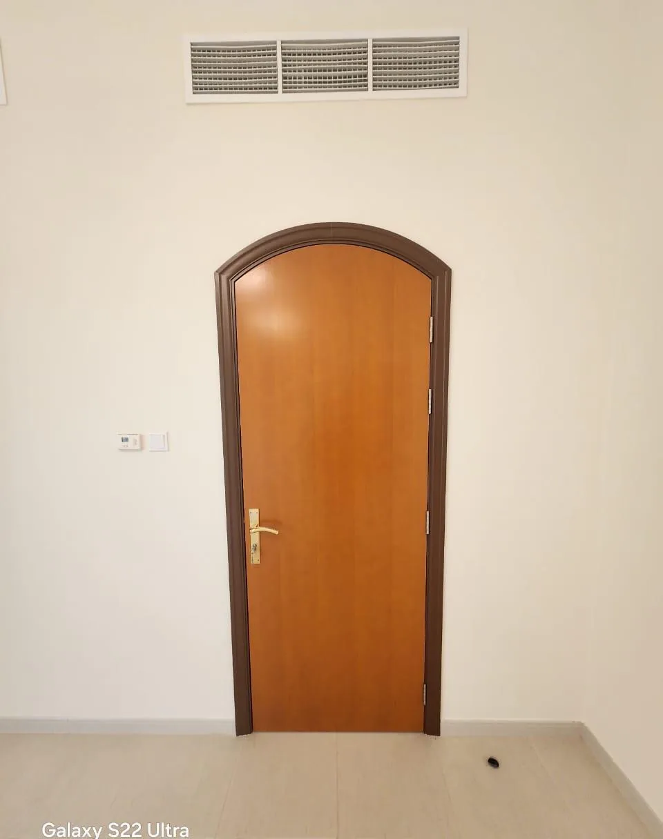 Arched wooden door with a smooth honey-coloured finish and brass handle