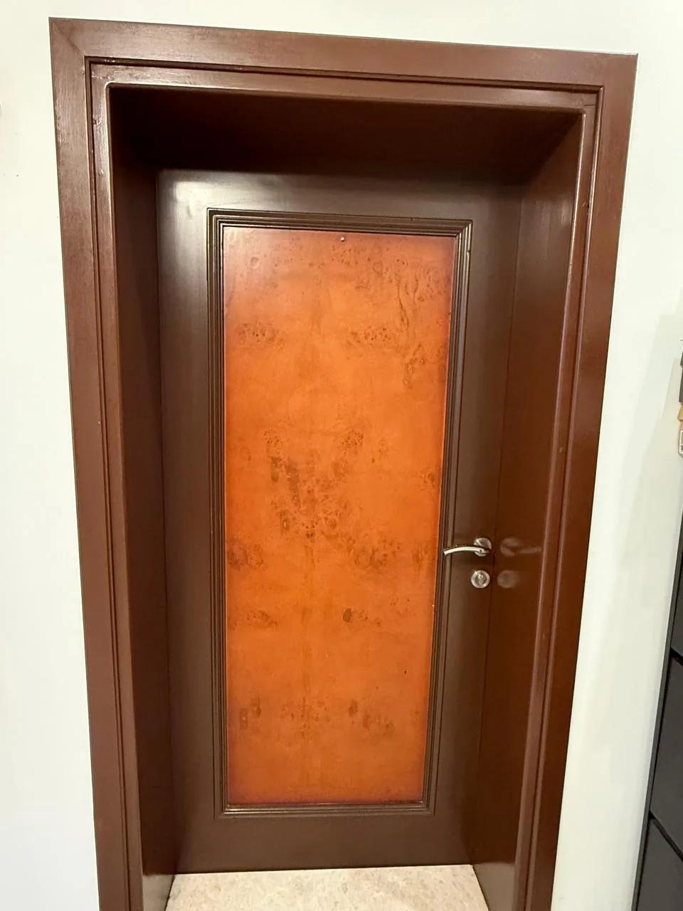 Interior door with a burl-wood style panel and a dark brown frame