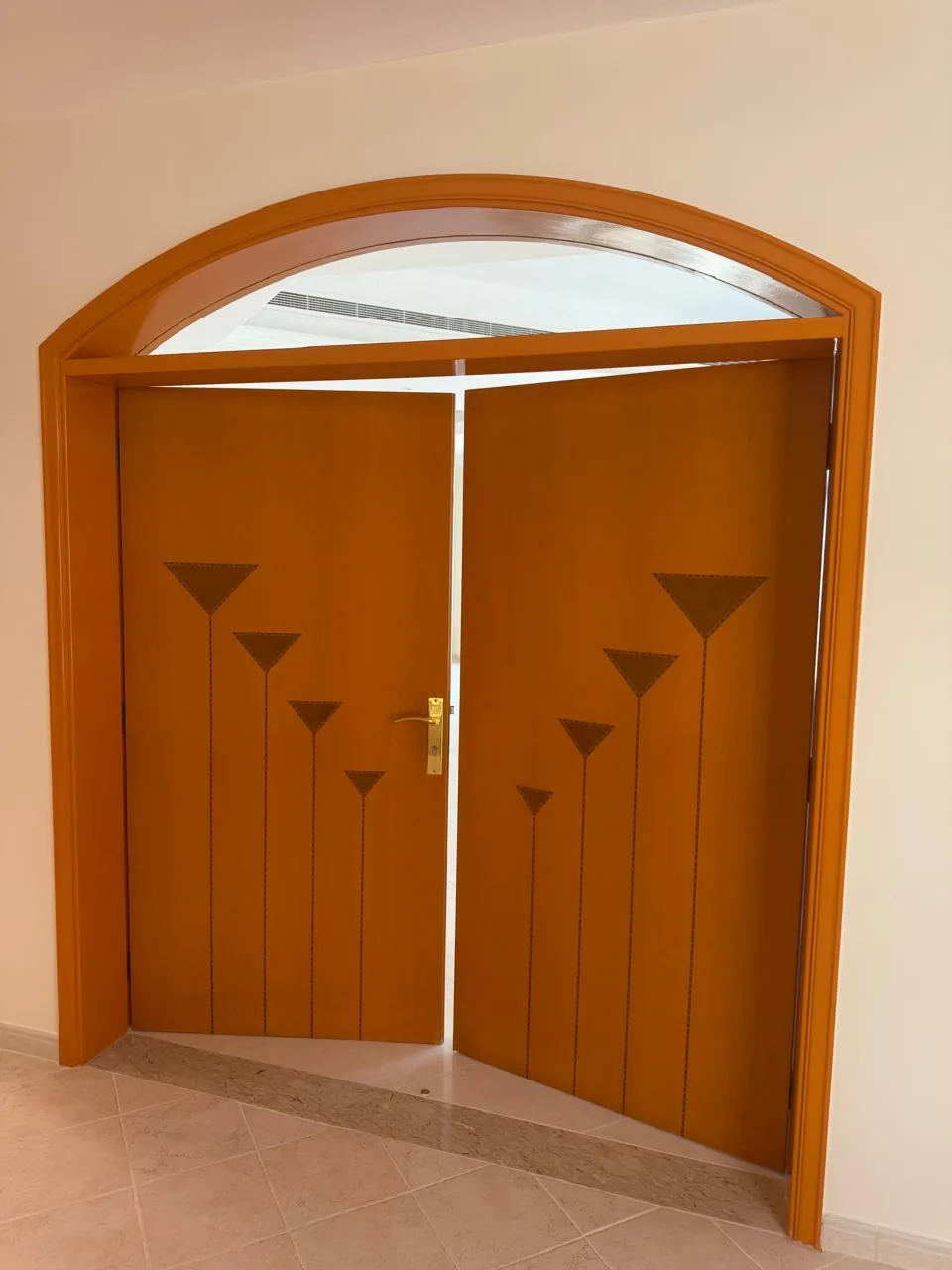 Double wooden doors with an arched fanlight and inlay design